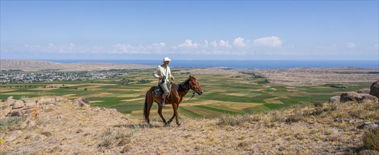 Young man on a horse in the mountains, tourist riding, near Bokonbayevo, Issyk Kul region,