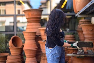 A woman handles terracotta pots at a pottery workshop