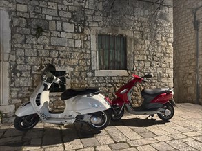 Two Vespas parked in front of an old stone wall at night, Trogir, Dalmatia, Croatia, Europe