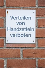 Distribution of flyers prohibited, warning sign on a brick wall on an architectural building in the