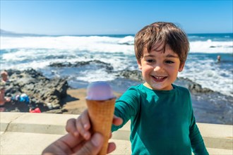 Father giving the child a delicious ice cream by the sea in summer. Family vacation concept