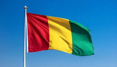 The flag of Guinea, fluttering in the wind, isolated, against the blue sky