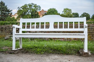 White wooden bench in the castle park of Dargun Castle and Monastery, in Dargun, Mecklenburg Lake