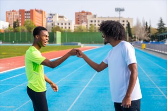 Two happy and smiling young african runners fist bumping in greeting before training on an outdoor