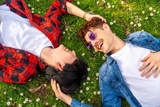 Top view of a multiracial gay couple enjoying spring lying on a park together