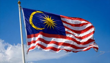 The flag of Malaysia, fluttering in the wind, isolated, against the blue sky