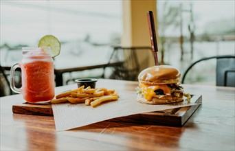 Delicious Hamburger with fries and strawberry cocktail served on a wooden table. Hamburger with
