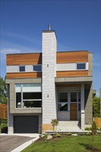 Two story grey and charcoal stone with cedar wood siding modern cube style home facade in summer,