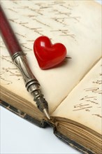 Pen with pen holder and red heart on diary