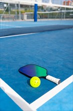 Vertical photo with copy space of a racket and yellow pickleball ball on a court
