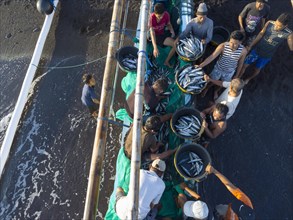 Fishermen unload their catch from their outrigger boat in the morning. Amed, Karangasem, Bali,