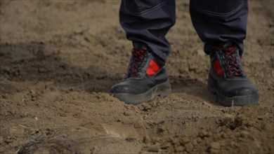 Close up of human feet in black shoes on muddy ground