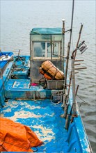 A close-up of a boat's cabin with fishing gear, highlighting the wear and decay, in South Korea