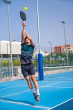 Vertical full length photo of a caucasian young sportive man jumping to reach the ball playing