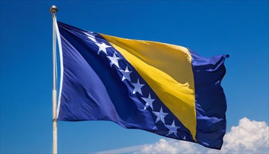 The flag of Bosnia and Herzegovina flutters in the wind, isolated against a blue sky