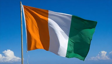The flag of Ivory Coast flutters in the wind, isolated, against the blue sky