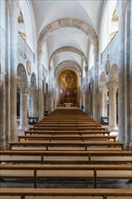 Interior of a church with stone benches and columns, flooded with natural light, Bad Reichenhall,