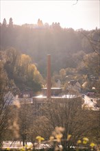 Industrial chimney rises into a sky at sunset with trees, spring, Calw, Black Forest, Germany,