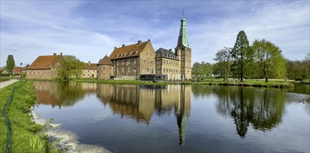 View over wide moat to historic moated castle from Renaissance Raesfeld Castle reflected in moat in