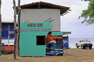 San Juan del Sur, Nicaragua, Colourful surf school with mural on the beach and parked car, Central