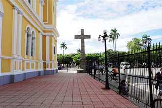 Granada, Nicaragua, forecourt of a yellow church with a large cross, surrounded by a wrought-iron