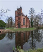 The Catholic Church of St Helena in Ludwigslust Castle Park is reflected in the water of a pond,