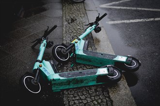 Two e-scooters lying on the road in the rain, taken in Berlin, 19/04/2024