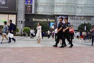 Chongqing, Chongqing Province, China, Asia, A police patrol walks through a shopping district, past
