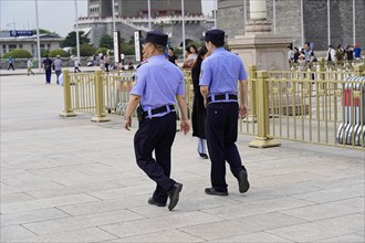 Beijing, China, Asia, Two uniformed security guards walk on a paved square in an urban