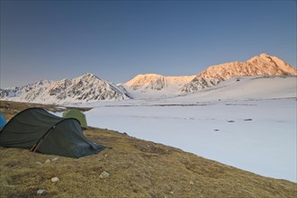 Icy tents in expedition camp at sunrise over the mountain peaks in the snow-covered Tavan Bogd
