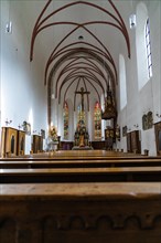 Interior view of a church with wooden pews and coloured stained glass windows, Bad Reichenhall,