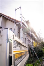 A scaffold with ladder stands on a house in the sunlight, solar systems construction, craft,