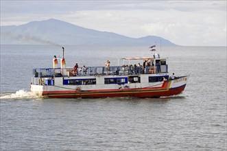 Lake Nicaragua, behind the island of Ometepe, ferry with passengers on the open sea, waving flag