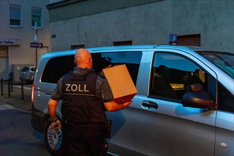 Customs officer at work, carrying cardboard to the official vehicle at dusk, The Cologne police led