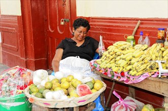 Granada, Nicaragua, A woman sells fruit at a stall on the street under a shady roof, Central