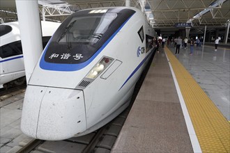 Express train CRH380 to Yichang, A high-speed train waits at a platform with passing passengers,