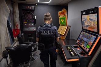 Customs officer looks at slot machines and surveillance equipment in a dark room, The Cologne