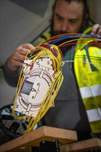 Electrician works concentrated on the wiring of technical devices, Galsfaserbau, Calw, Black