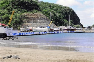 San Juan del Sur, Nicaragua, sandy beach beach with a large welcome sign and boats in the