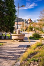 A village square with a fountain and a view of a castle in the background, spring, Calw, Black