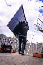 A craftsman installs a solar panel on a roof, solar systems construction, crafts, Muehlacker,