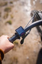 A hand operates a bicycle speedometer on the handlebars of a bicycle near a cycle path, spring,