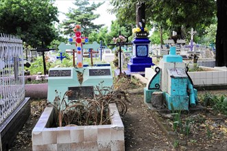 Leon, Nicaragua, A cemetery with colourful crosses and graves surrounded by vegetation, Central