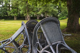Four chairs are grouped around a table under a tree in a park, St George's Monastery, Isny im