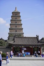Traditional Chinese pagoda under a clear blue sky with visitors in front of it, Chongqing,
