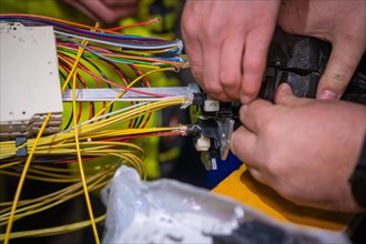 Close-up of an electrician's hands working on a complex wiring harness, Galsfaserbau, Calw, Black