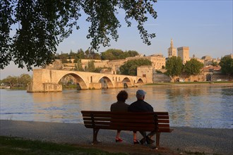 Couple on a park bench on the banks of the Rhone, Pont Saint Benezet bridge, Palais des Papes and