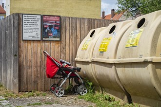 Pushchair left in front of a recycling container in the old town centre of Memmingen, Swabia,