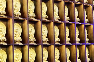 Jade Buddha temple, Shanghai, rows of small golden Buddha figures on shelves as wall decoration,