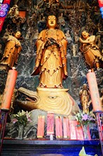 Jade Buddha Temple, Shanghai, Large gold-coloured statue in Asian style with red candles and flower